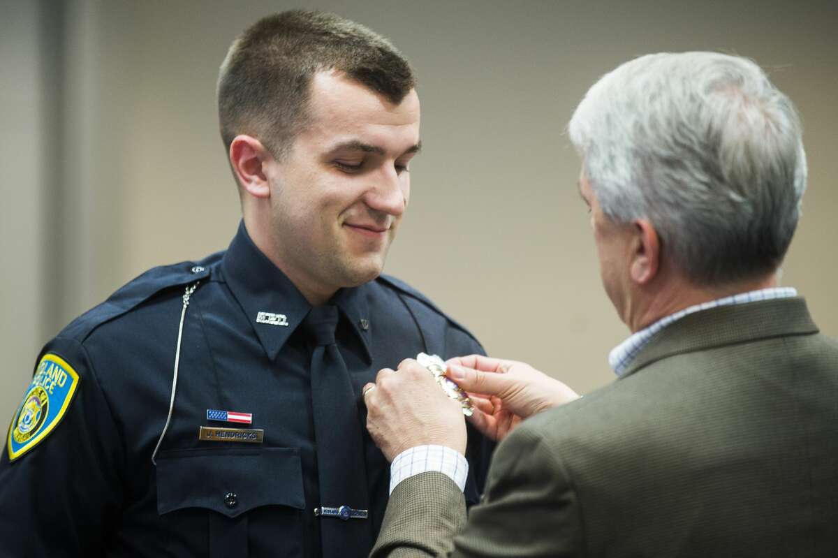 Officer Jay Hendricks of the Midland Police Department, left, has his badge pinned to his uniform by Rich Hendricks, right, during a swearing-in ceremony on Tuesday, June 4, 2019 at City Hall. (Katy Kildee/kkildee@mdn.net)