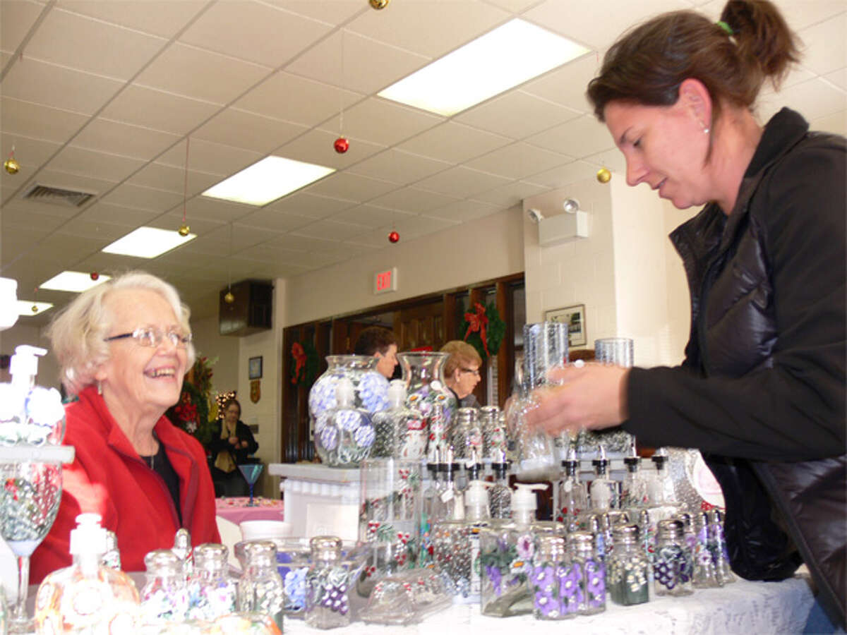 Debra McGlone, right, of Shelton looks at painted glass items being sold by crafter Sandy Beauton of Derby at the fair.