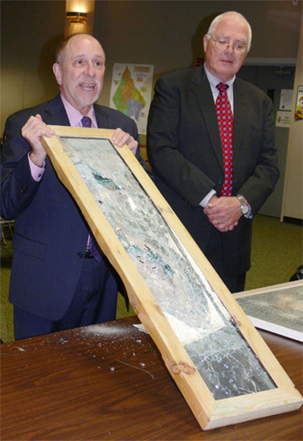 School Supt. Freeman Burr, left, shows a security film-coated window that withstood gun shots and other damage to the Board of Aldermen, with school Finance Director Al Cameron at his side.