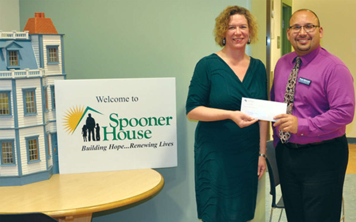 Susan Agamy, executive director of Spooner House, accepts a donation from Paolo Mancuso, branch manager of Sikorsky Credit Union’s Shelton office.