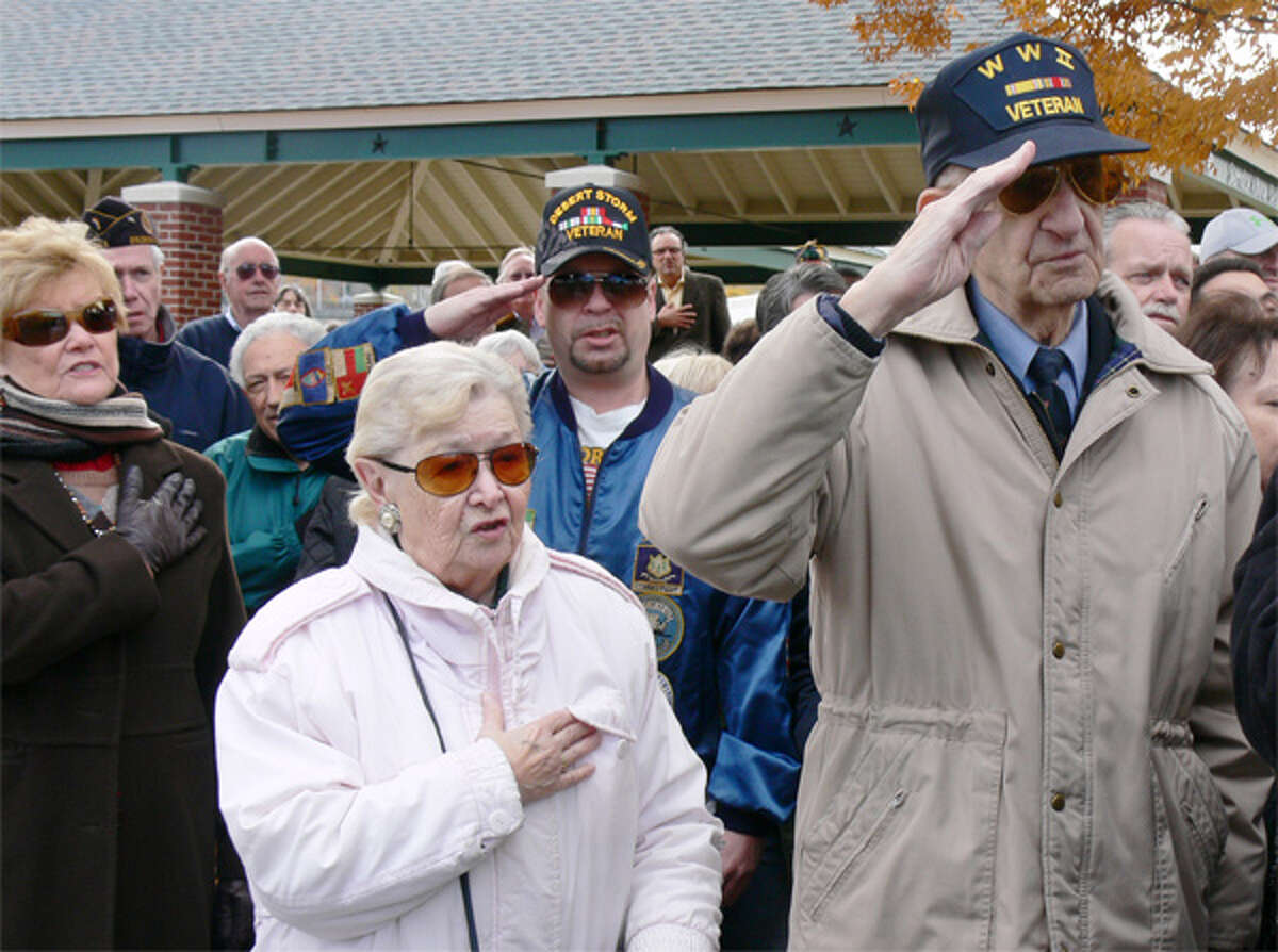 People in the crowd salute and stand at attention during the 2013 Shelton Veterans Day ceremony.