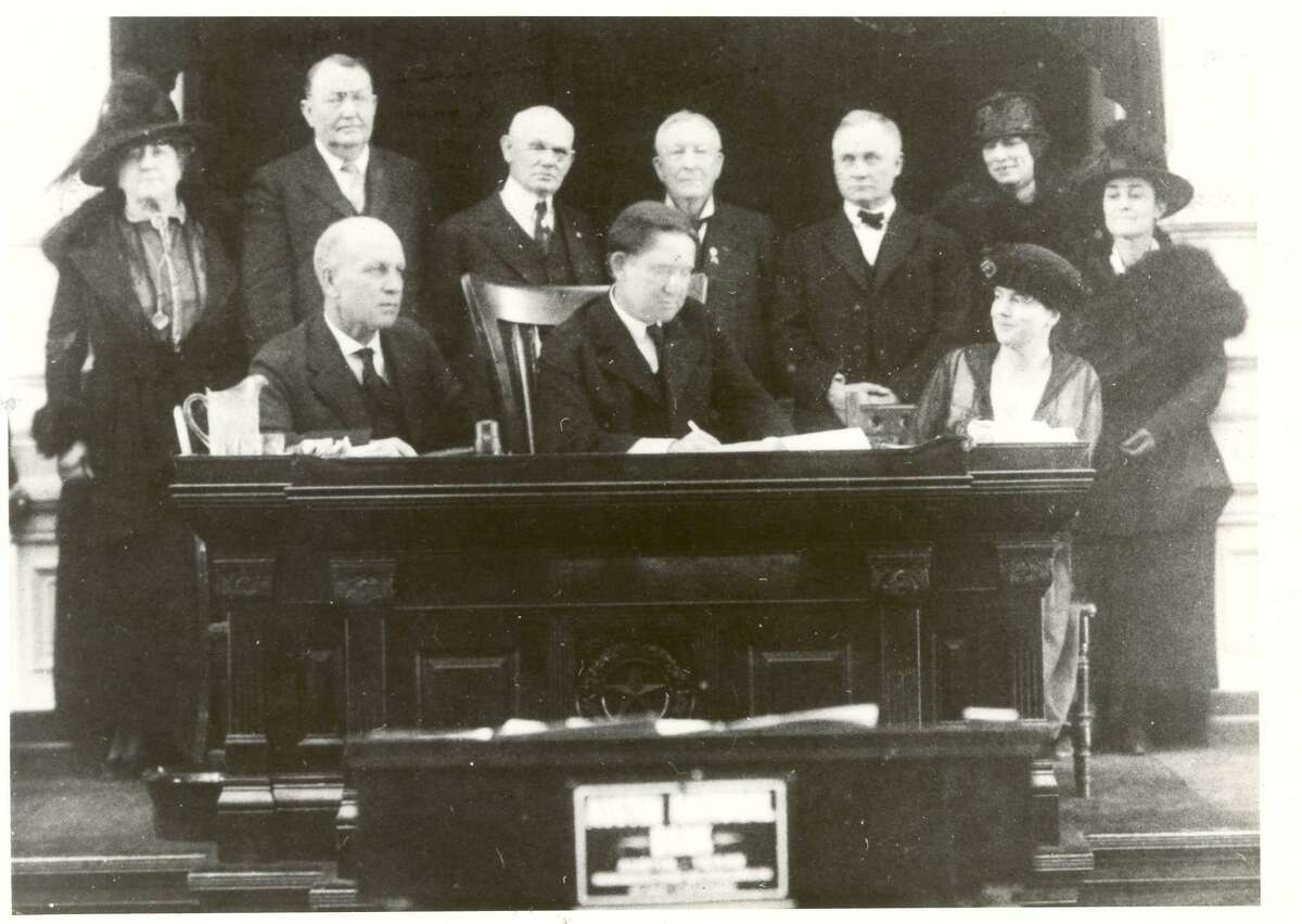 Texas Gov. William P. Hobby signs the Texas Woman Suffrage Resolution in a ceremony in the Texas Senate on Feb. 5, 1919. Minnie Fisher Cunningham, Texas senate leaders and other sponsors of the suffrage movement look on.