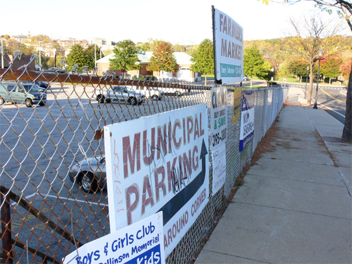 A view of the chain-link fence around the municipal parking lot that will be replaced by a safer, more decorative fence. The Farmers Market Building is in the background.