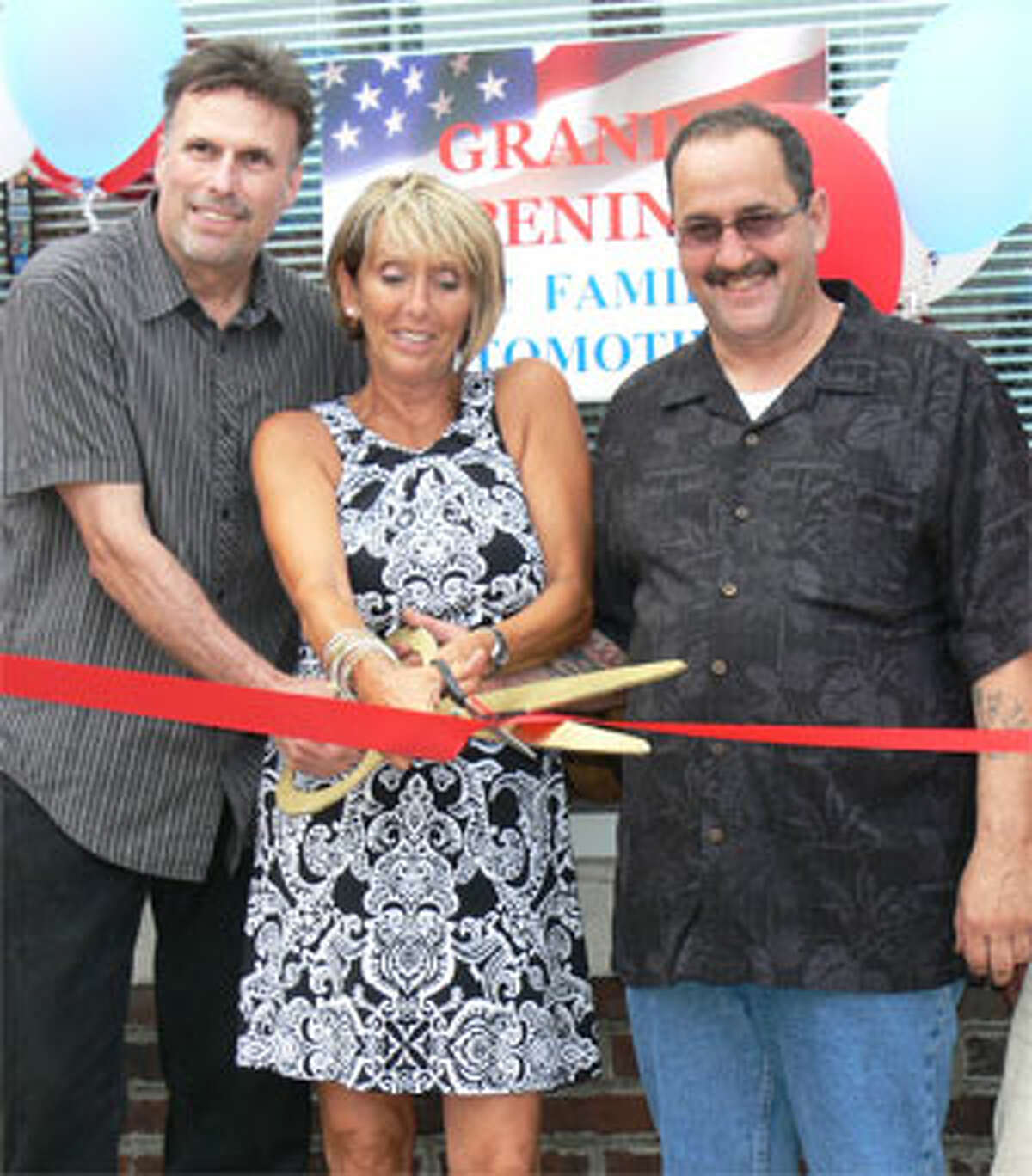 Renee Capece cuts the ceremonial ribbon while joined by William F. Constantino, left, and her husband Anthony Capece at C&C Family Automotive in Shelton.