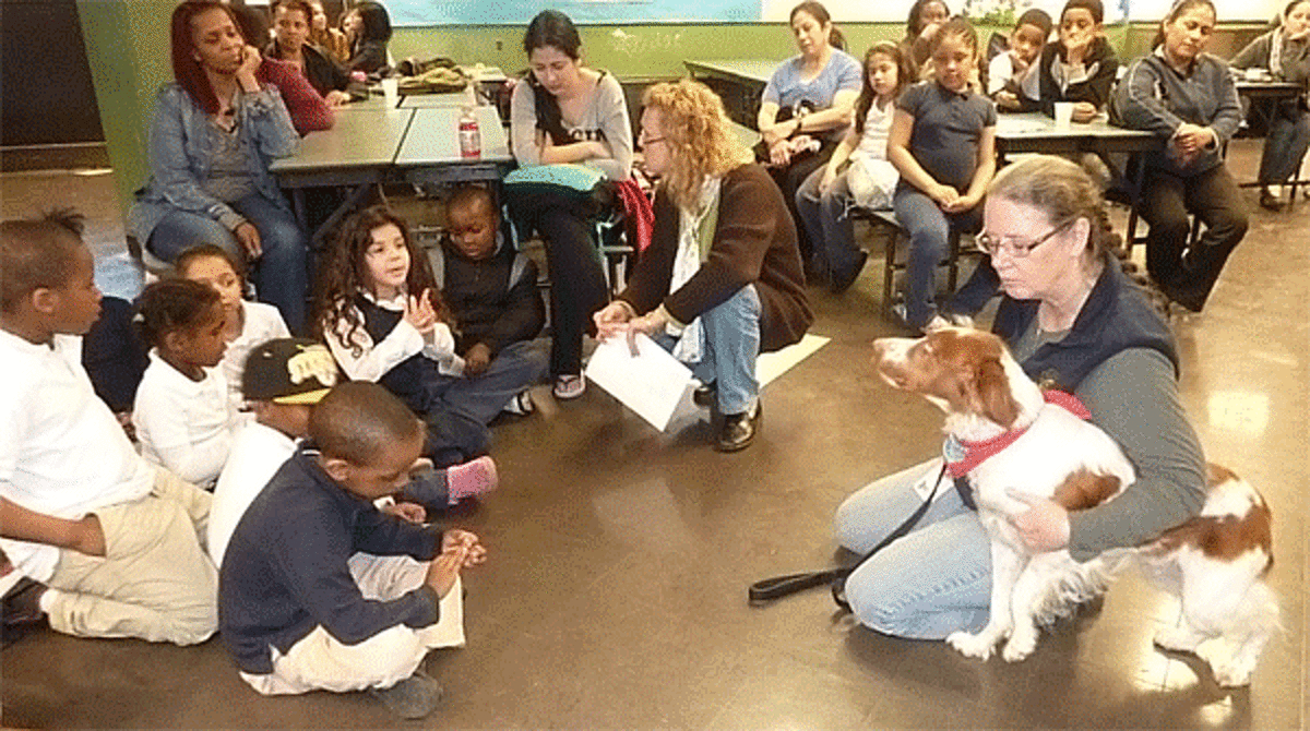 Multicultural Magnet School students interact with Trap Falls Kennel Club President Laura Wells of Shelton, center, and club member Dona Campbell, who is with one of her therapy dogs, Hannah.