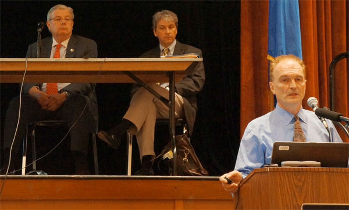 Charles V. Firlotte, far right, president and CEO of Aquarion, speaks during a recent Public Utilities Regulatory Authority hearing on Aquarion's proposed rate increase, as PURA officials look on in the background. (Photo by Shawn O’Sullivan)