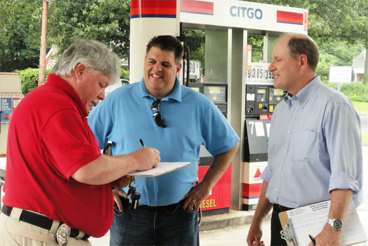 State Sen. Kevin Kelly, right, and state Rep. Dave Rutigliano, center, collect signatures opposing a gas tax increase at a Shelton gas station.