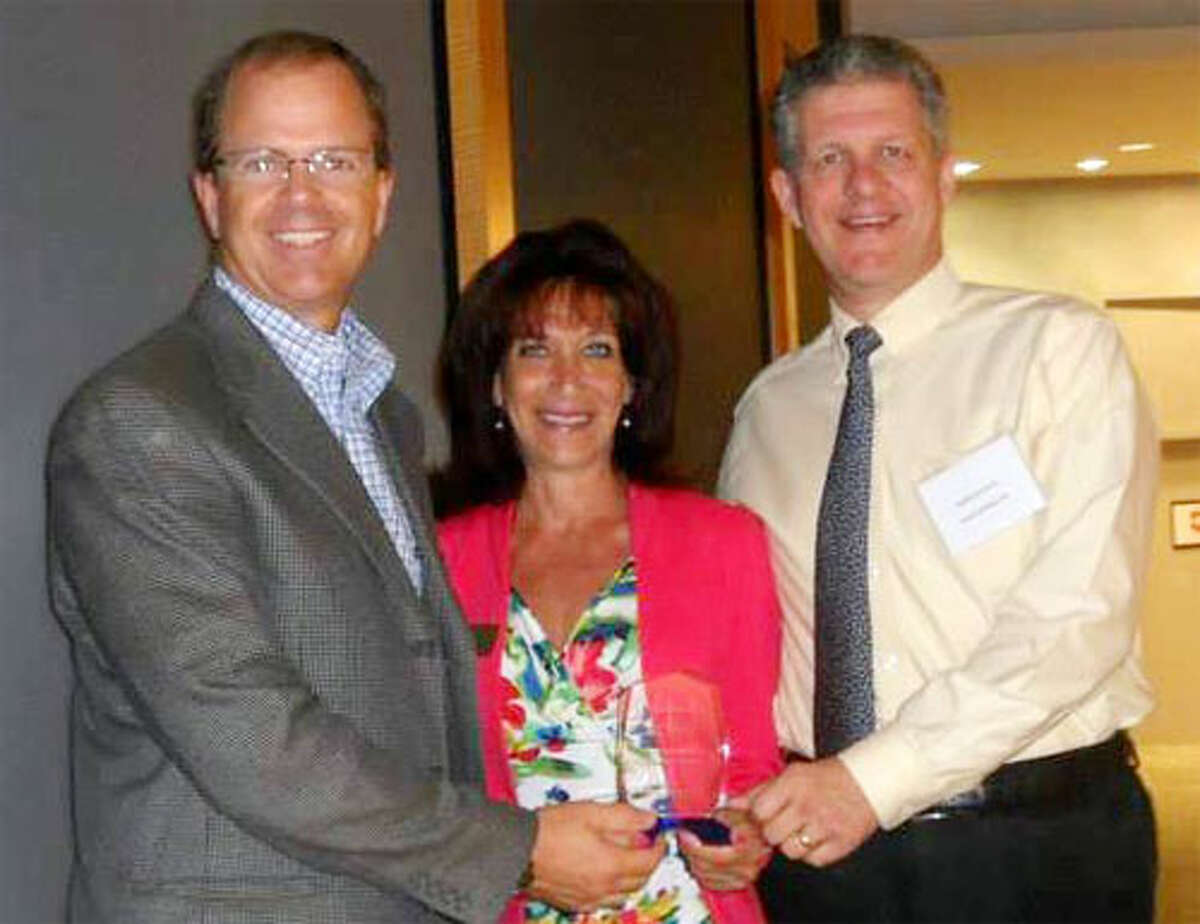 Local Junior Achievement resident Bernadine Venditto, center, presents the Outstanding Corporate Partner Award to Shelton-based Gexpro representatives Jim Hibberd and Bradford Greene.