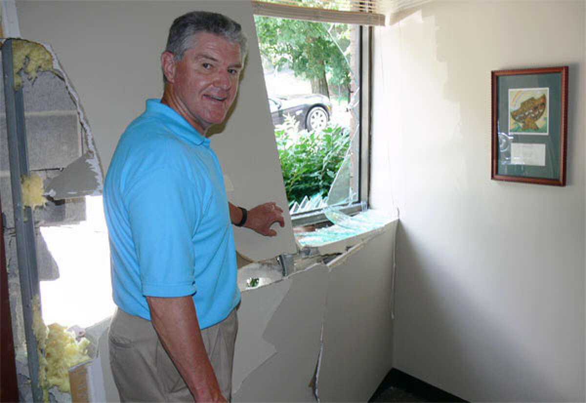 John Discko stands near the wall in his Shelton office that a car smashed into on Monday morning. (Photos by Brad Durrell)