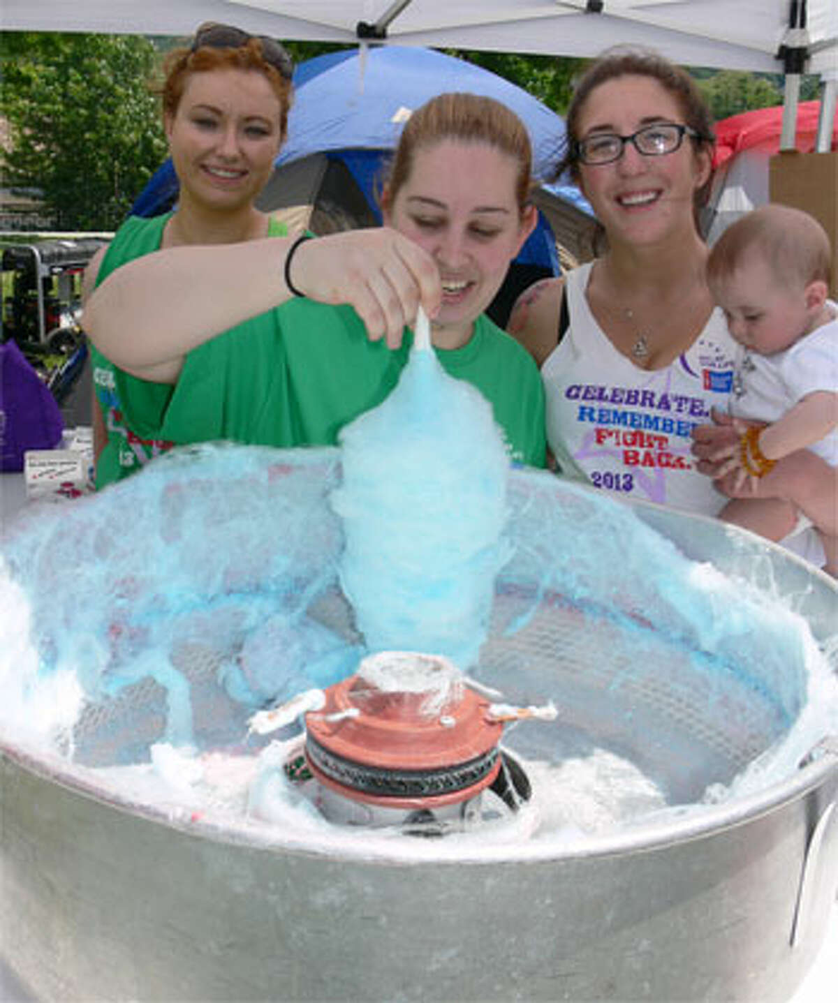 Mary Silva of Shelton makes cotton candy while joined by Cynthia Messaoudi of Seymour, left, and Maryann Linebarger of Shelton, right, who is holding Mary’s daughter, Zoe, age 6 months. They were representing a family-based team named Saving Second Base.