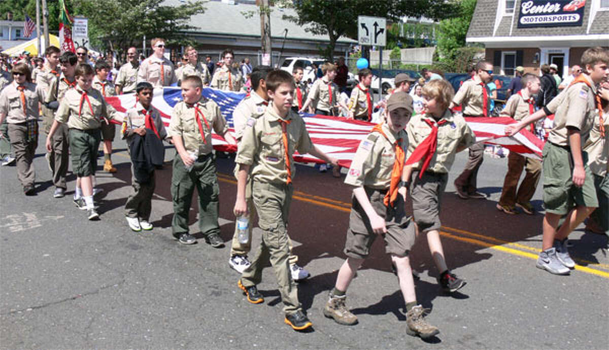 A Shelton Boy Scout troop holds a large American flag while marching on Center Street in the 2013 Memorial Day parade.