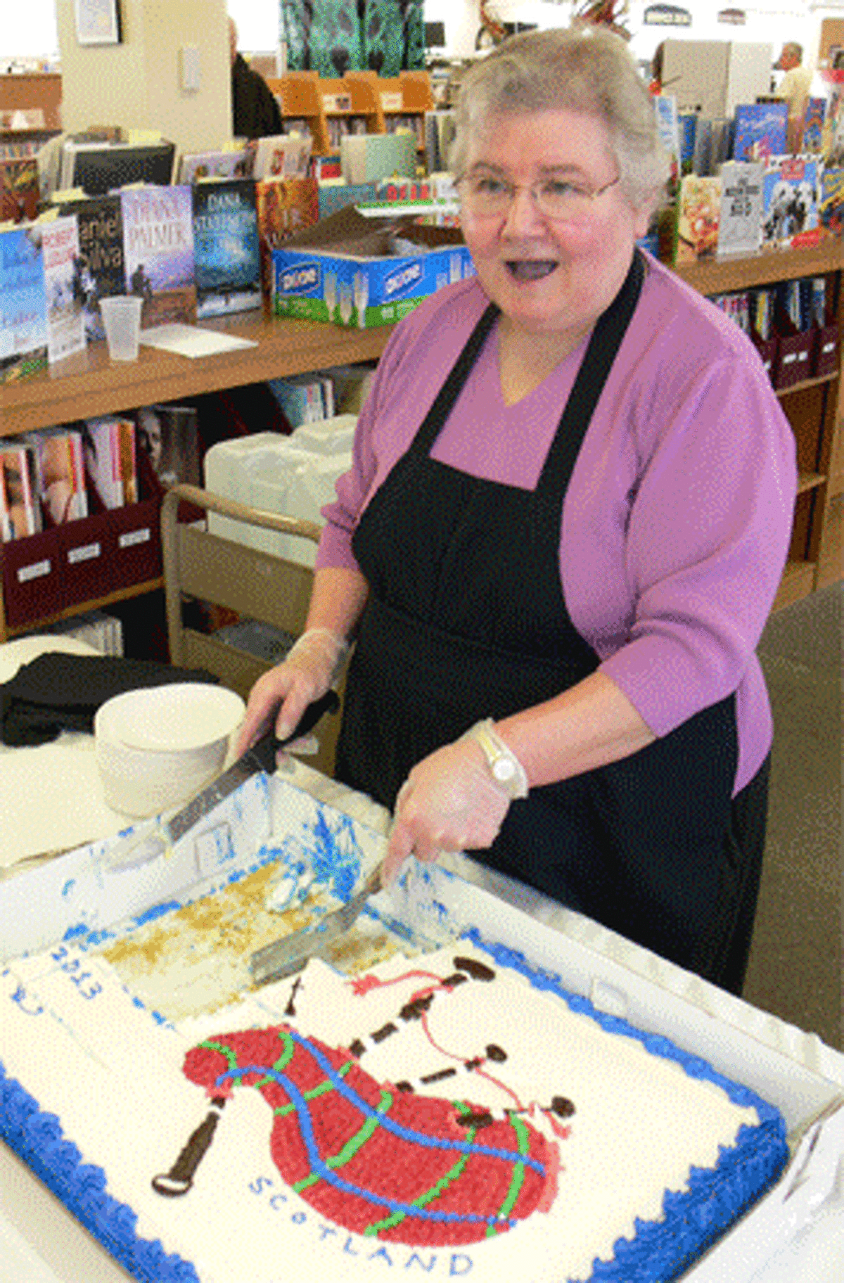 Jo Ann Patters, a library volunteer from Shelton, was distributing cake with a Scottish bagpipe design at the Huntington Branch Library open house.