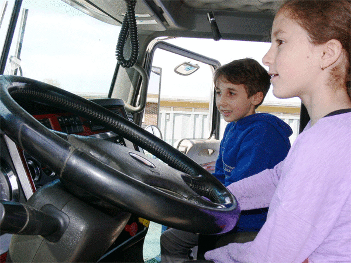 Lia Leandres, 8, gets behind the wheel of a J.J. Brennan Construction truck, joined by friend Luke Moraveck.