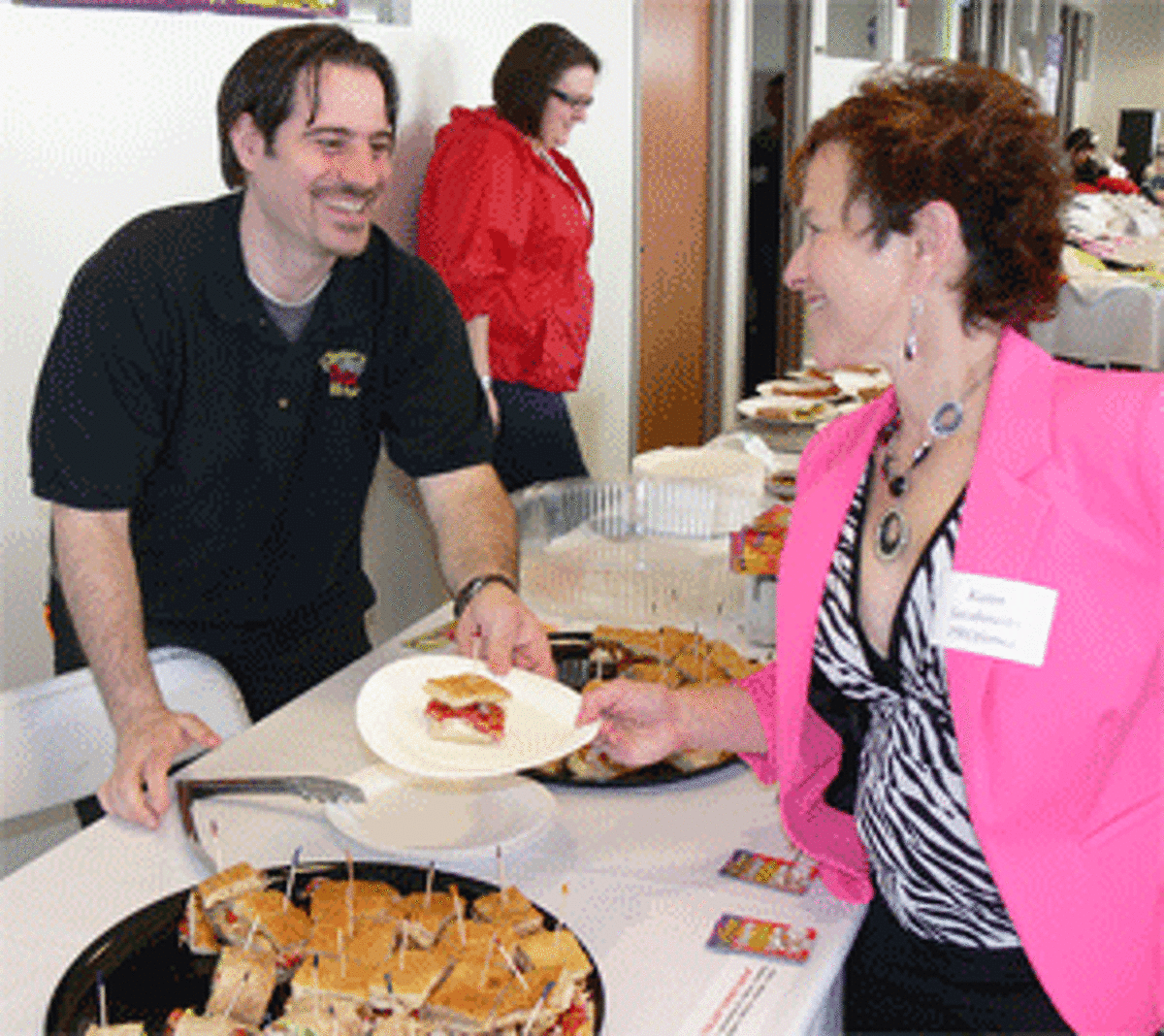Joe DeVellis of Giove’s Pizza Kitchen hands a piece of focaccia to Karen Jacobowitz of Proforma, a printing, promotions and branding company, during the 2013 chamber expo.