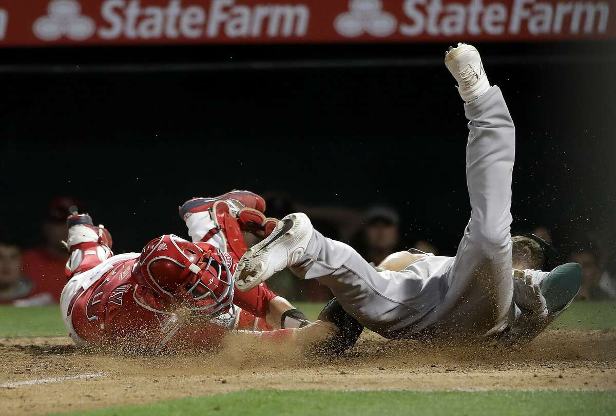 Oakland Athletics' Matt Chapman, right, scores on a wild pitch past Los Angeles Angels catcher Jonathan Lucroy during the eighth inning of a baseball game Wednesday, June 5, 2019, in Anaheim, Calif. (AP Photo/Marcio Jose Sanchez)
