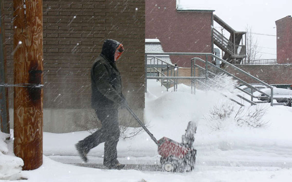 A man uses a snowblower to clear snow from the sidewalk near the Dunkin’ Donuts at Howe Avenue and Center Street.