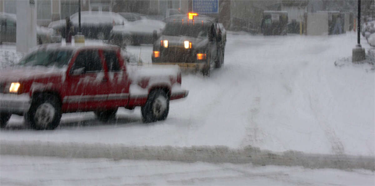 Vehicles, including a private plow, on the move late Thursday afternoon in Shelton as the snow began to accumulate.