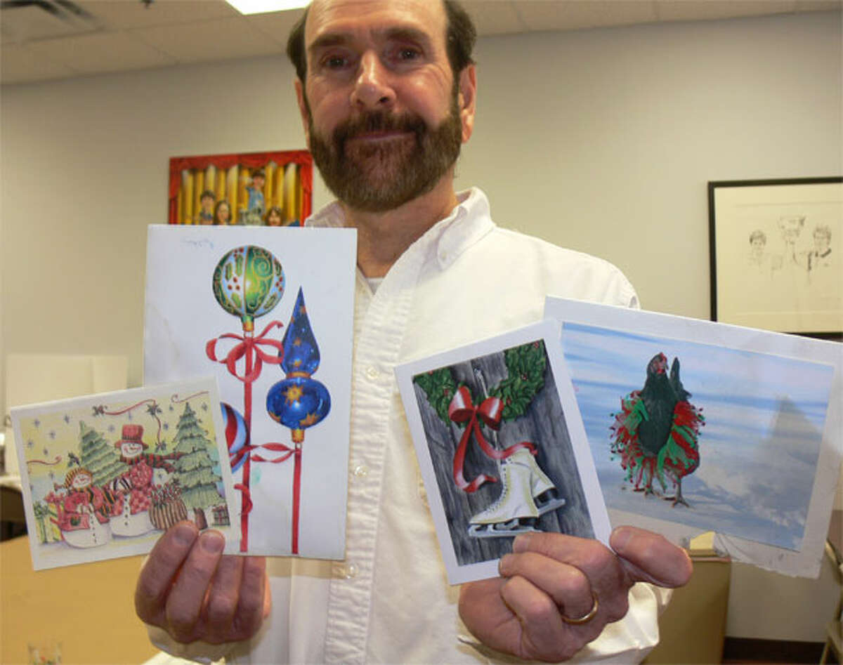 Bob Boroski holds holiday cards made by students at his art school through the years that survived the massive downtown fire last January. Some of the cards are charred from the blaze and most still smell of smoke.