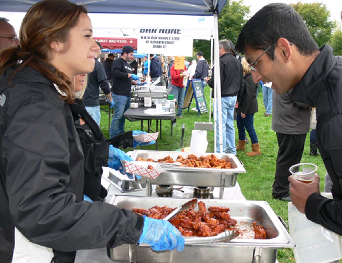 Carly Paul, left, of Porky’s in downtown Shelton prepares to dish out some wings to a hungry festival-goer.