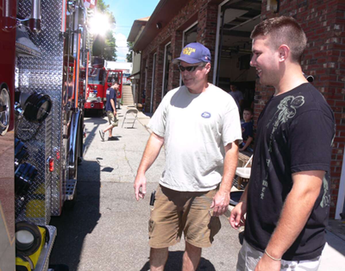 Brian McCue, center, and his son Dan, 21, on right, both White Hills volunteer firefighters, check out the new fire truck during the “wet-down” at the White Hills Fire Station.
