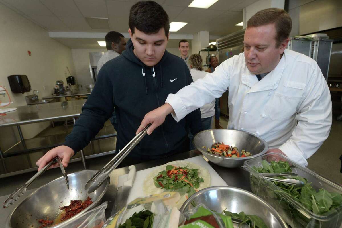 Senior Jake Lovo gets help from culinary teacher Ted White as they prepare food for faculty members during the Norwalk High School culinary program Wednesday, January 10, 2018, at the school in Norwalk, Conn. The culinary program may become a certificate program through a partnership with Norwalk Community College.