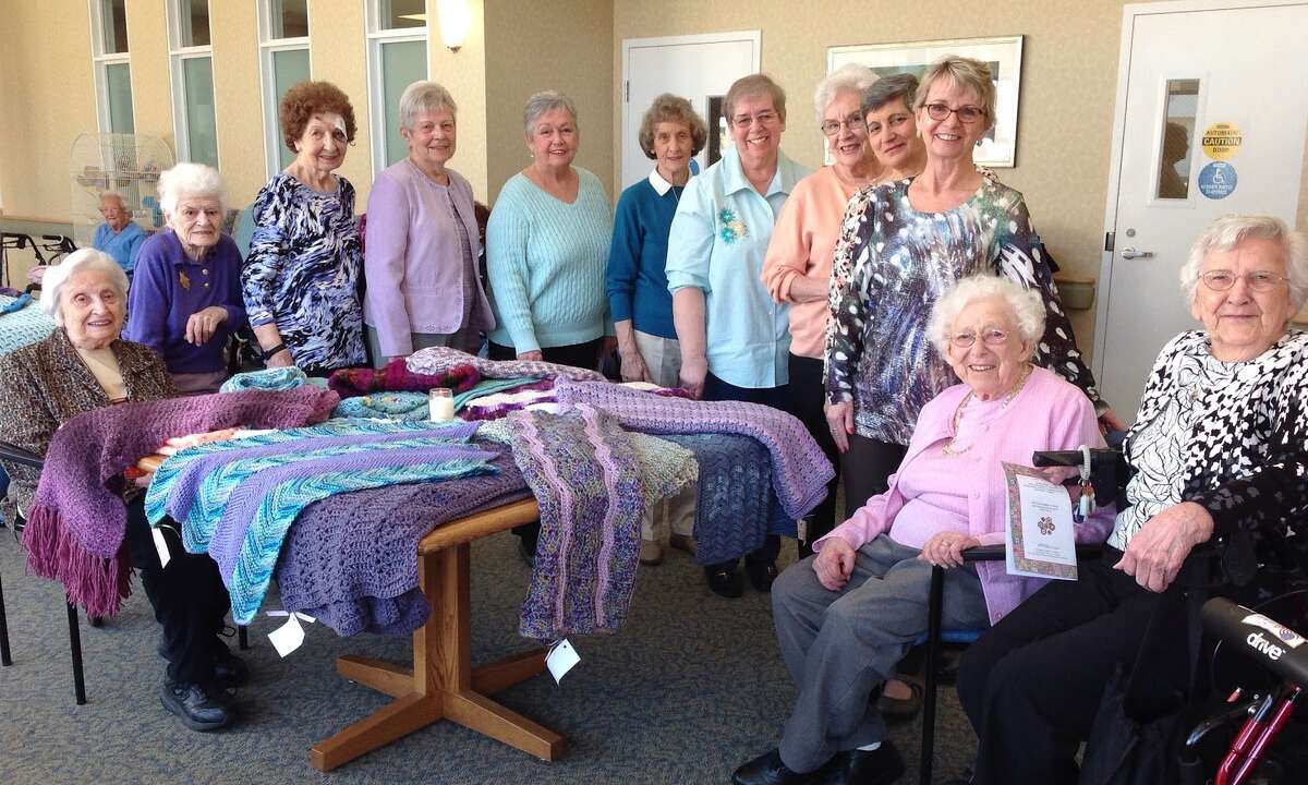 Members of the Wesley Village knitting group gather for a photo during an annual Prayer Shawl Blessing. The group of staff, residents, and volunteers knits shawls and blankets for those in need throughout the year.