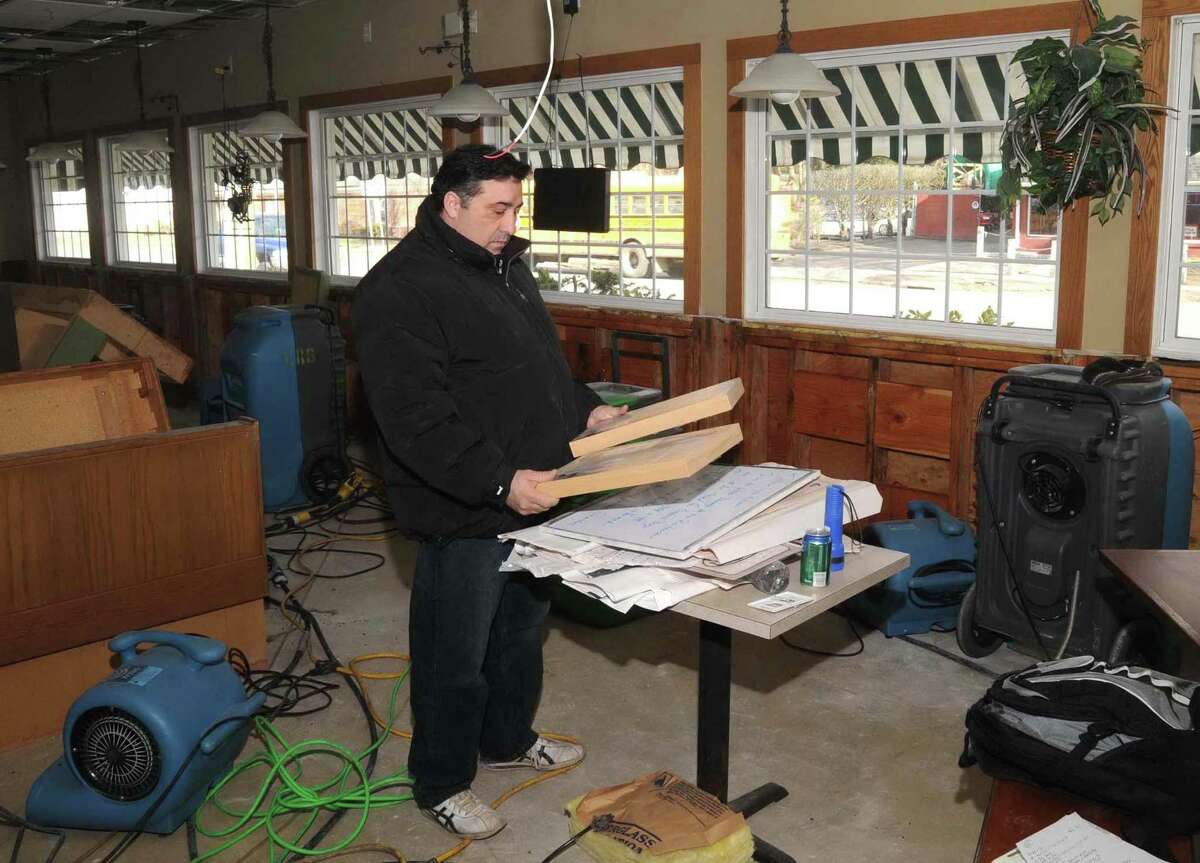 Tony Fernandes, owner of Tonelli's Restaurant, in Bethel, CT, holds two pictures from the restaurants dining room. The restaurant has been close because of major water damage from a burst water pipe. Photo: Wednesday, Jan. 20, 2010.