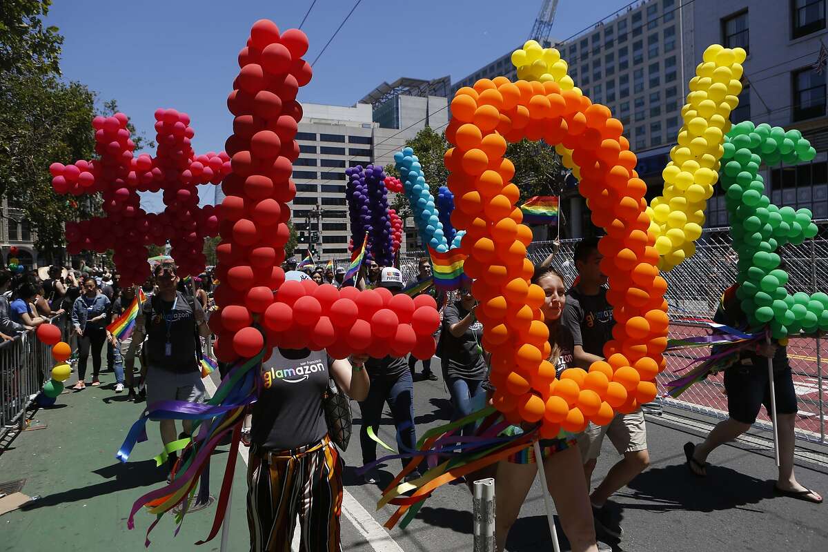Pride Parade participants carry Love signs down Market Street on Sunday, June 24, 2018 in San Francisco, Calif.