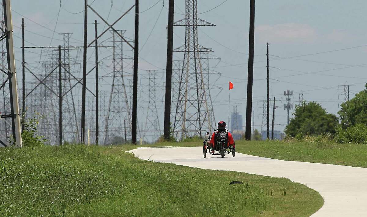 Carl Pointer rides his recumbent bicycle on the new recreational trail along a CenterPoint Energy easement near Hiram Clarke Road and Sims Bayou on June 8.