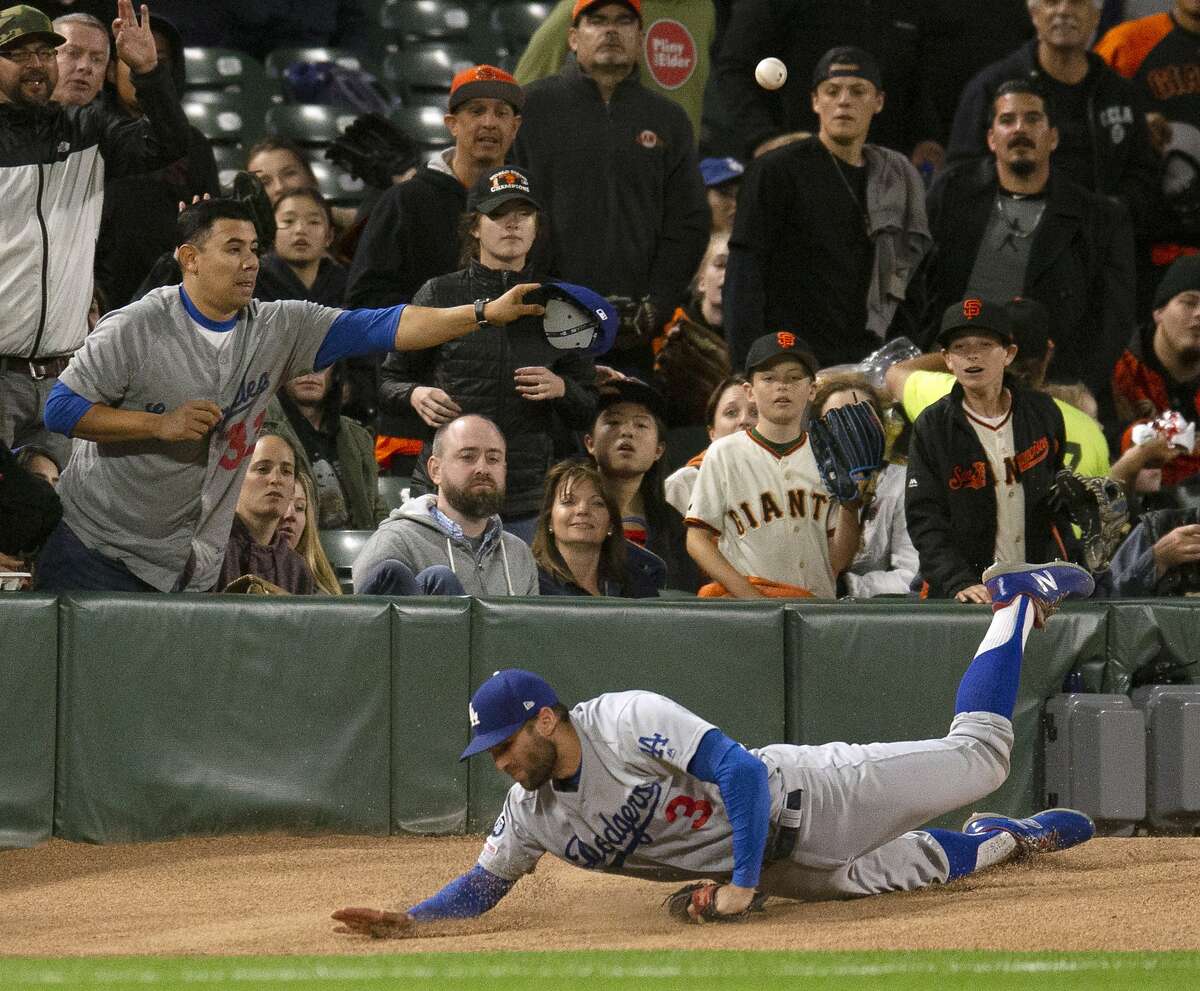Los Angeles Dodgers left fielder Chris Taylor trips over the bullpen pitcher's mound while chasing a foul ball by San Francisco Giants' Brandon Belt during the sixth inning of a baseball game, Friday, June 7, 2019, in San Francisco. Belt eventually walked and scored. (AP Photo/D. Ross Cameron)