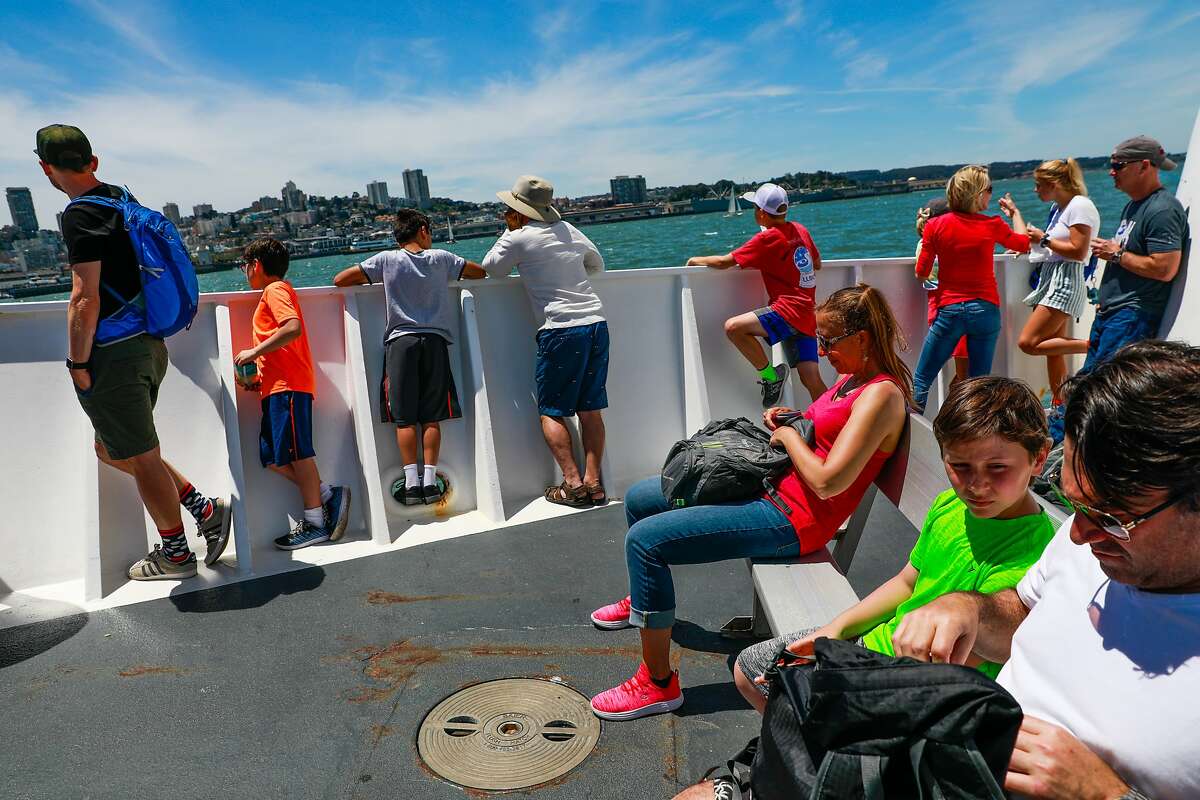 People sit out in the sun as they ride the boat from Alcatraz to San Francisco in San Francisco, California, on Sunday, June 9, 2019.