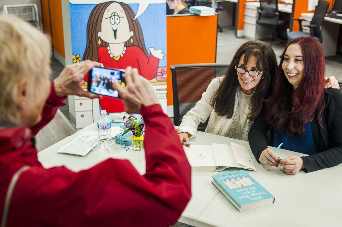 A woman takes a photo of Cathy Guisewite, a local cartoonist and author, left, and her daughter Ivy, right, during a book signing on Monday, June 10, 2019 at the Midland Daily News office on Main Street in Midland. (Katy Kildee/kkildee@mdn.net)