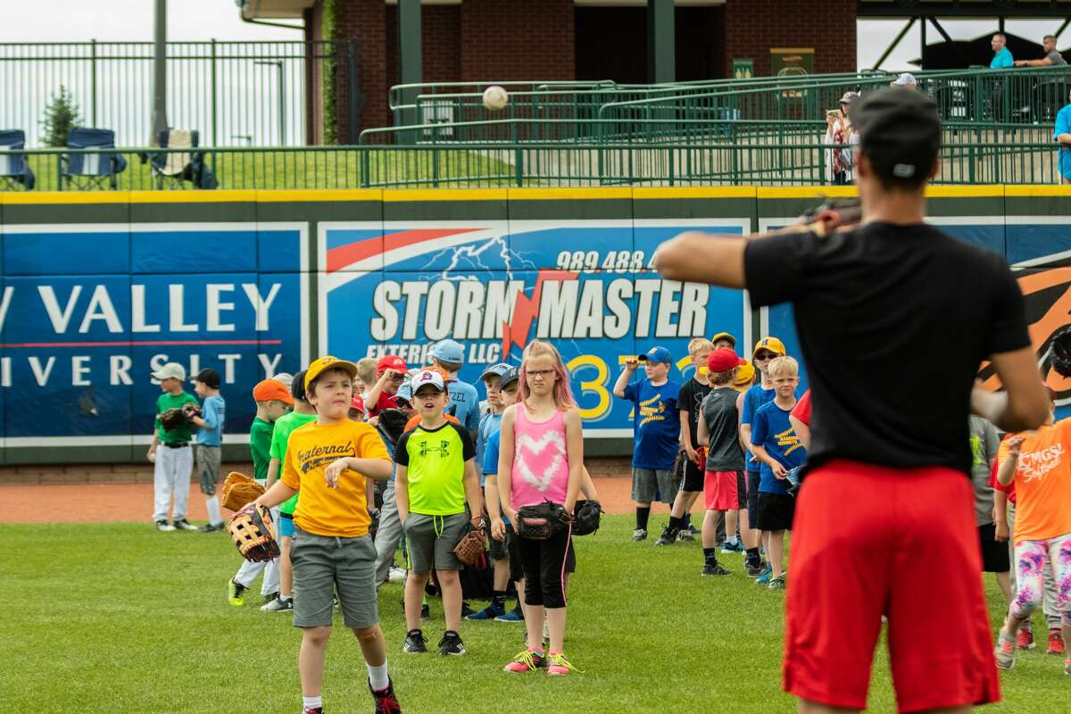 A Loons players gives instruction to kids during the Youth Baseball Clinic before Sunday's win over South Bend at Dow Diamond.