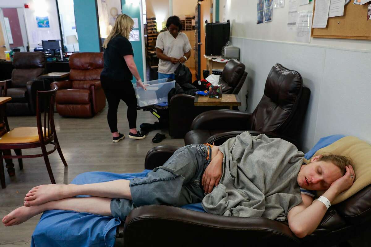 Lindsey Cassidy (bottom) sleeps as Breanna Blueford (top,right) gets her belongings together at the Dore Urgent Care clinic which is a crisis drop-in center for mental health needs in San Francisco, California, on Monday, June 10, 2019. Supervisors Matt Haney and Hillary Ronen have proposed a sweeping ballot measure to overhaul the city's mental health care system.