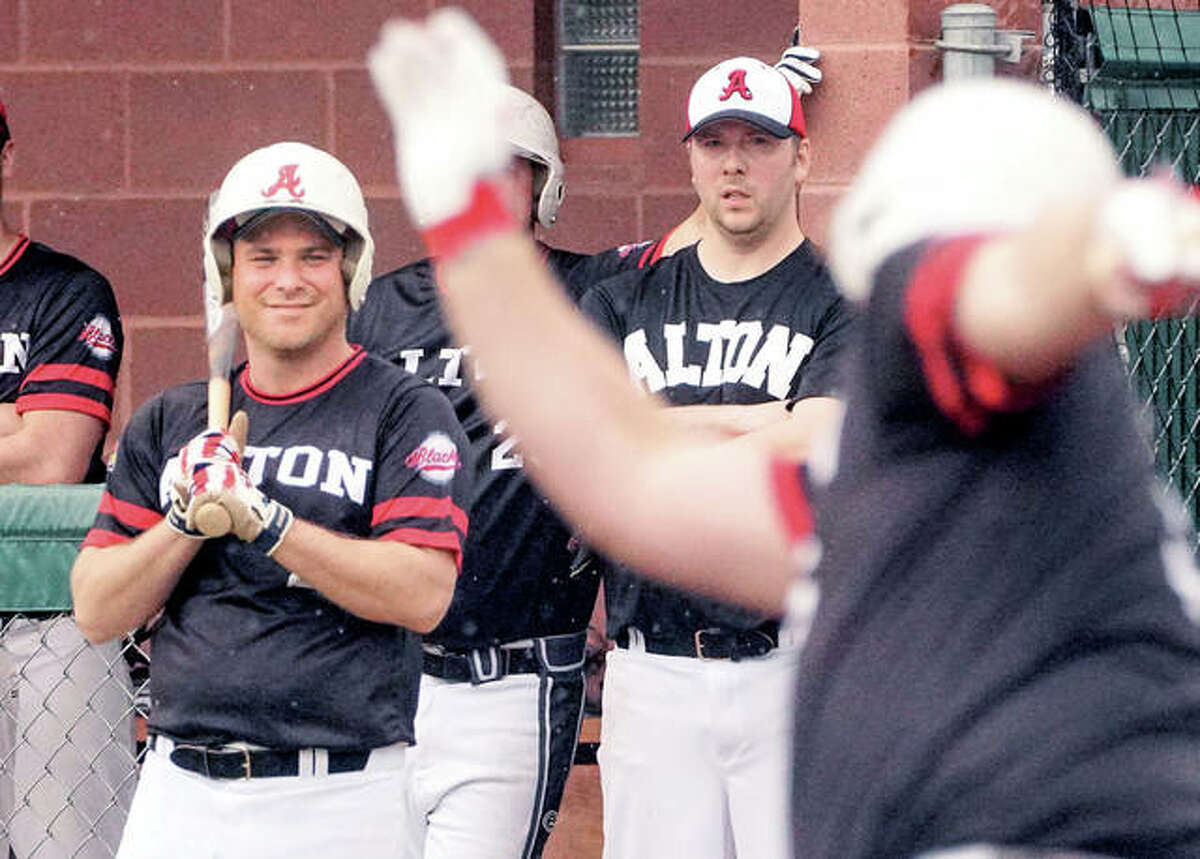 Matt Dorner, left, AHS Class of 2001, sports a smile while watching a former teammate take a swing Saturday during the inaugural Alton High School alumni baseball game. The event, which included 45 former players, included a silent auction to raise money for the Redbirds’ baseball program.
