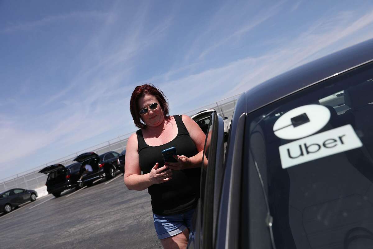 Uber driver Danielle Clark checks her phone for a pick up request as she waits in the TNC waiting lot on Wednesday, June 5, 2019 at San Francisco International Airport in San Francisco, Calif.