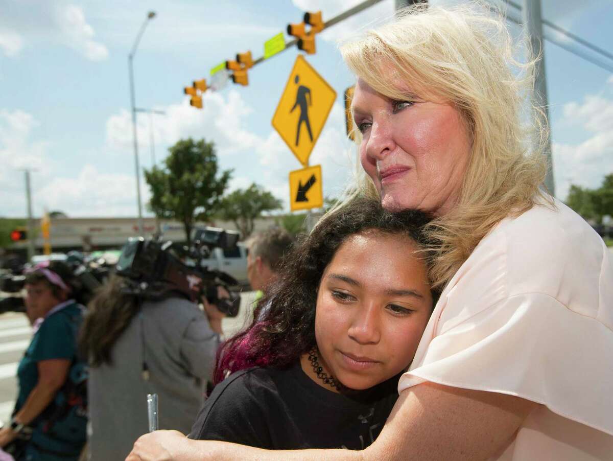 Teri Webb embraces her neice Ava Adams-Marsh near a newly-installed crosswalk light that was put in as part of the city's Safer Streets initiative on Monday, June 10, 2019, in Houston. The traffic signal was installed at the location where Lesha Adams was helping Jesus Perez, who was in a wheelchair, cross the street on March 30 and were hit and killed by a car at the intersection