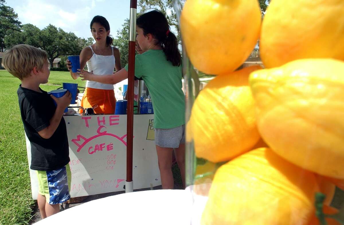Madeline, 12, center, and Caroline Stone, 9, right, hand John Bowman, 5, a cup of lemonade Wednesday, Aug. 2, 2006, at their neighborhood stand in Beaumont, Texas. (AP Photo/The Beaumont Enterprise, Andrew Nenque) ** MANDATORY CREDIT, MAGS OUT, NO SALES **