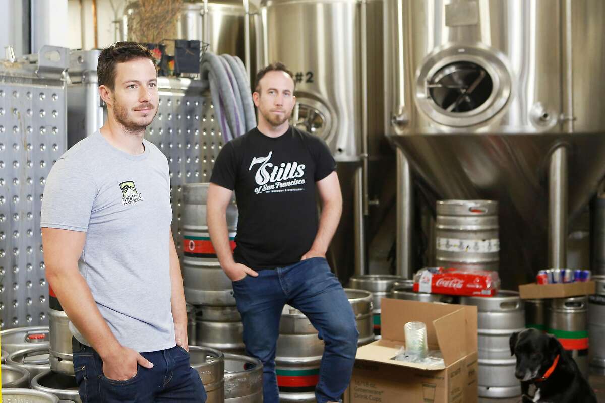 Founders Tim Obert, left, and Clint Potter, right, pose at their brewery Seven Stills on Egbert St. with pet dog Tango on Wednesday, June 20, 2018 in San Francisco, Calif. Although Seven Stills is only two years old, it's about to open its fourth location in the city.