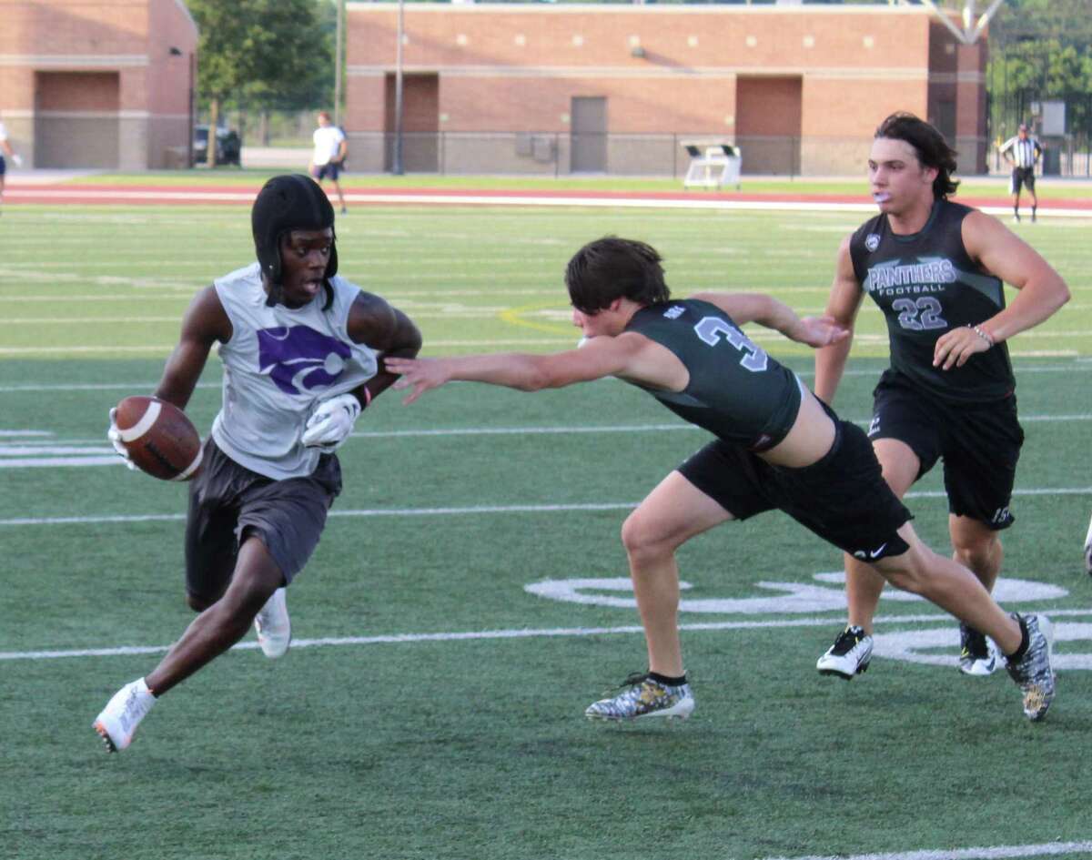 Humble wide receiver Nathan Green avoids Kingwood Park defenders during a 7-on-7 football game at Turner Stadium.
