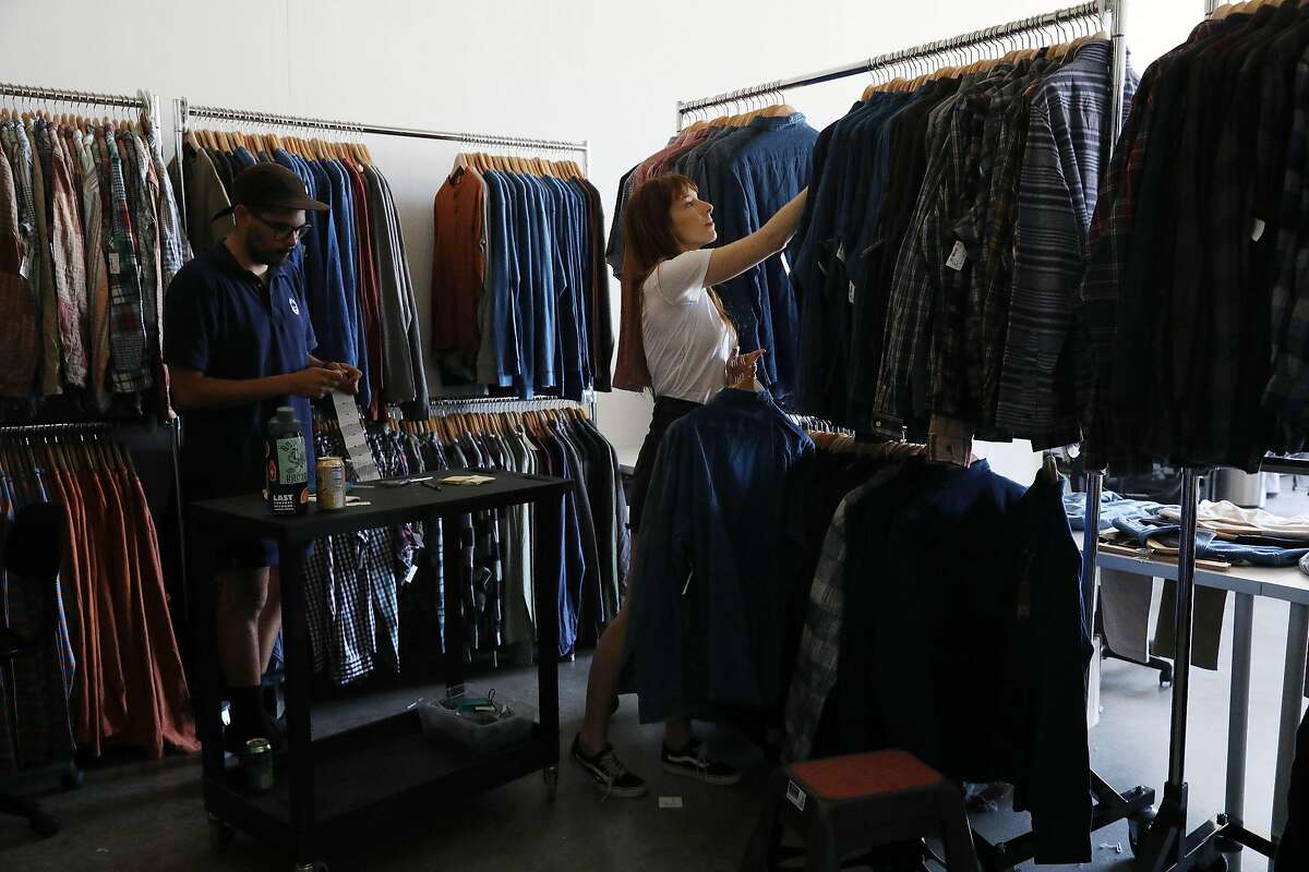 Andrew Garcia (l to r), inventory specialist, adds tags to clothing as Hayley Teubner, warehouse manager, coordinates merchandise for the stores as they work at the Cary Lane warehouse on Tuesday, June 11, 2019 in San Francisco, Calif.