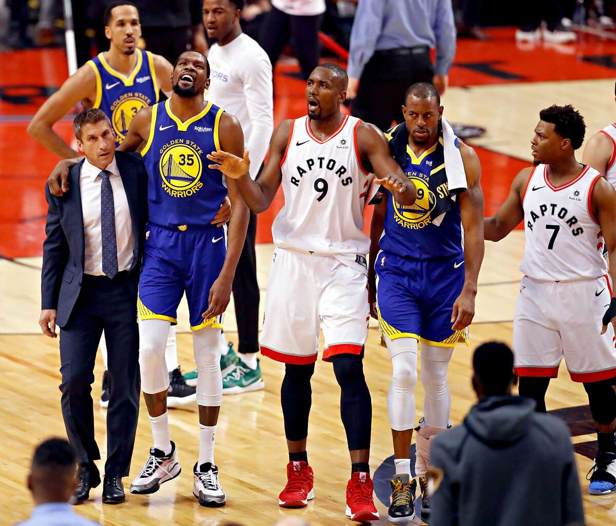 Golden State Warriors� Kevin Durant is helped off the court by the team�s director of sports medicine Rick Celebrini as Toronto Raptors� Serge Ibaka signals to the crowd in the first quarter during game 5 of the NBA Finals between the Golden State Warriors and the Toronto Raptors at Scotiabank Arena on Monday, June 10, 2019 in Toronto, Ontario, Canada.