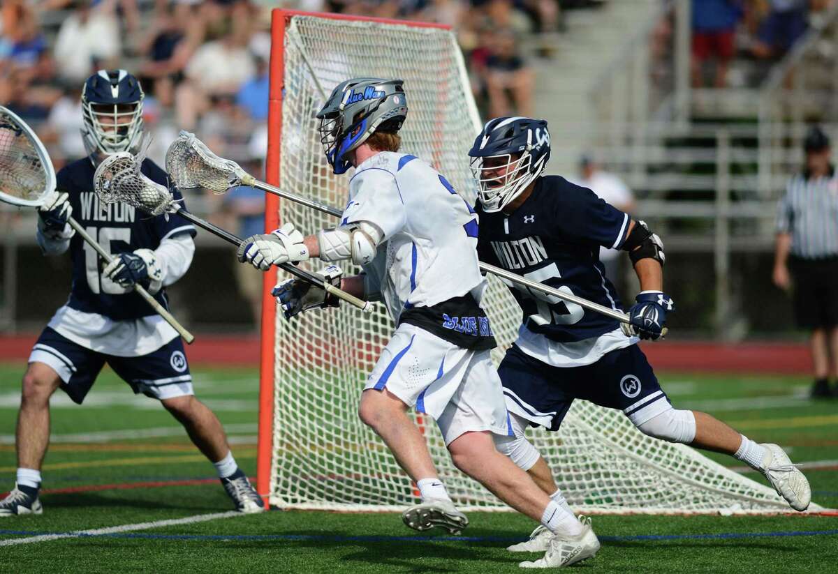 Darien’s Hudson Pokorny (3) bears down on Wilton goalie Andrew Calabrese and Drew Herlyn (35) in Saturday’s Class L championship.