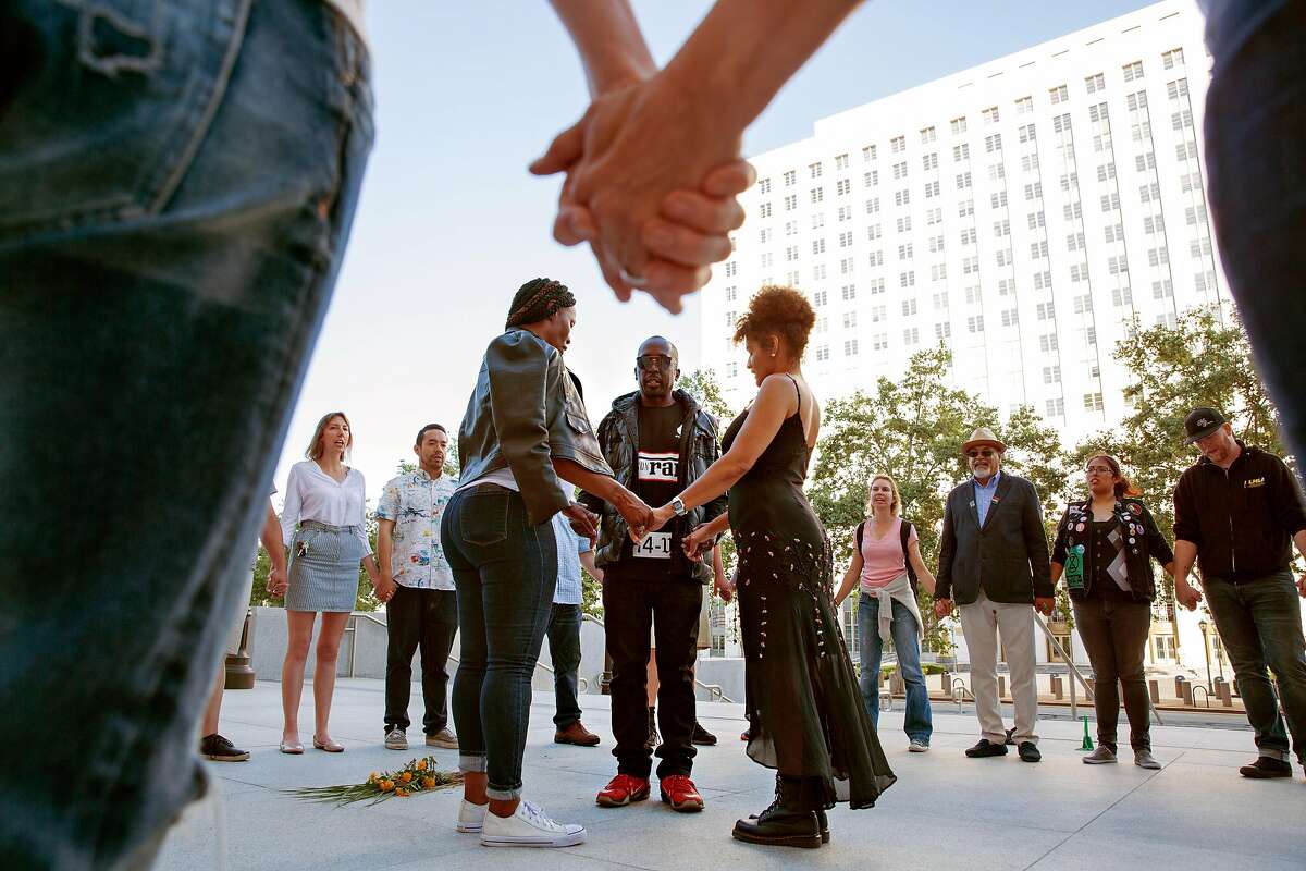 LOS ANGELES, CA - JUNE 12, 2019: Quintus Moore is in the center of 0 group of activists participate in a weekly protest outside the L.A. Hall of Justice, organized by LA Black Lives Matter, and is an activist for laws that would make it more difficult for law enforcement officers to resort to deadly force. Here they hold hands in prayer.