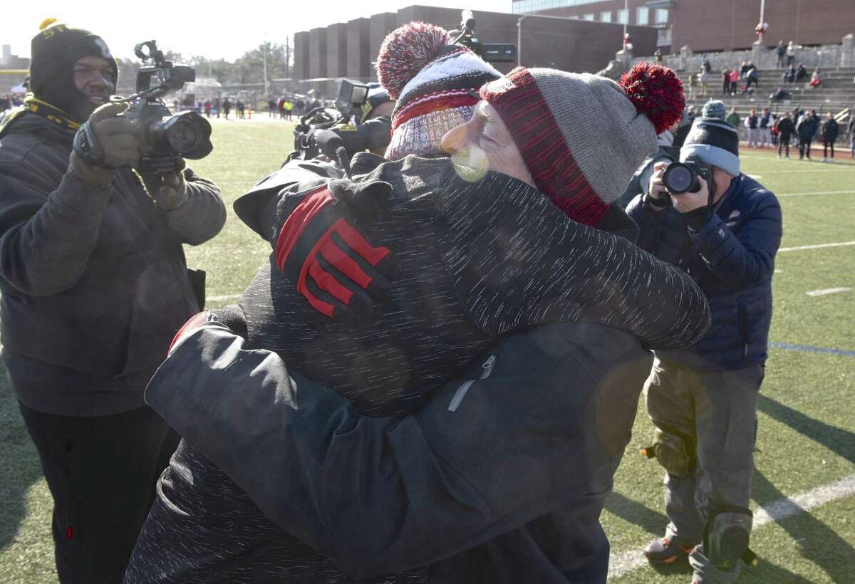 Greenwich head coach John Marinelli gets a hug from his father New Canaan head coach Lou Marinelli, right, after defeating his fathers team 34-0 in the Connecticut high school Class LL football championship game between Greenwich and New Canaan high schools, Saturday morning, December 8, 2018, at Boyle Stadium, Stamford High School, Stamford, Conn.
