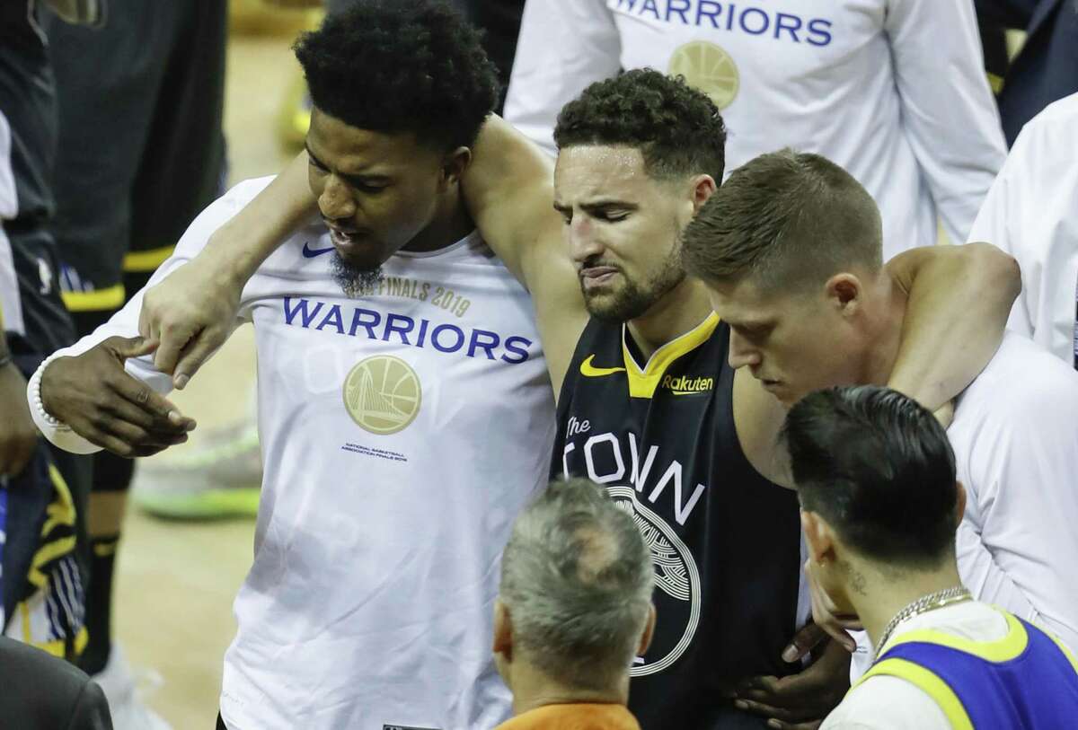 Golden State Warriors’ Klay Thompson is helped off the court by Jordan Bell and Jonas Jerebko in the third quarter during game 6 of the NBA Finals between the Golden State Warriors and the Toronto Raptors at Oracle Arena on Thursday, June 13, 2019 in Oakland, Calif.