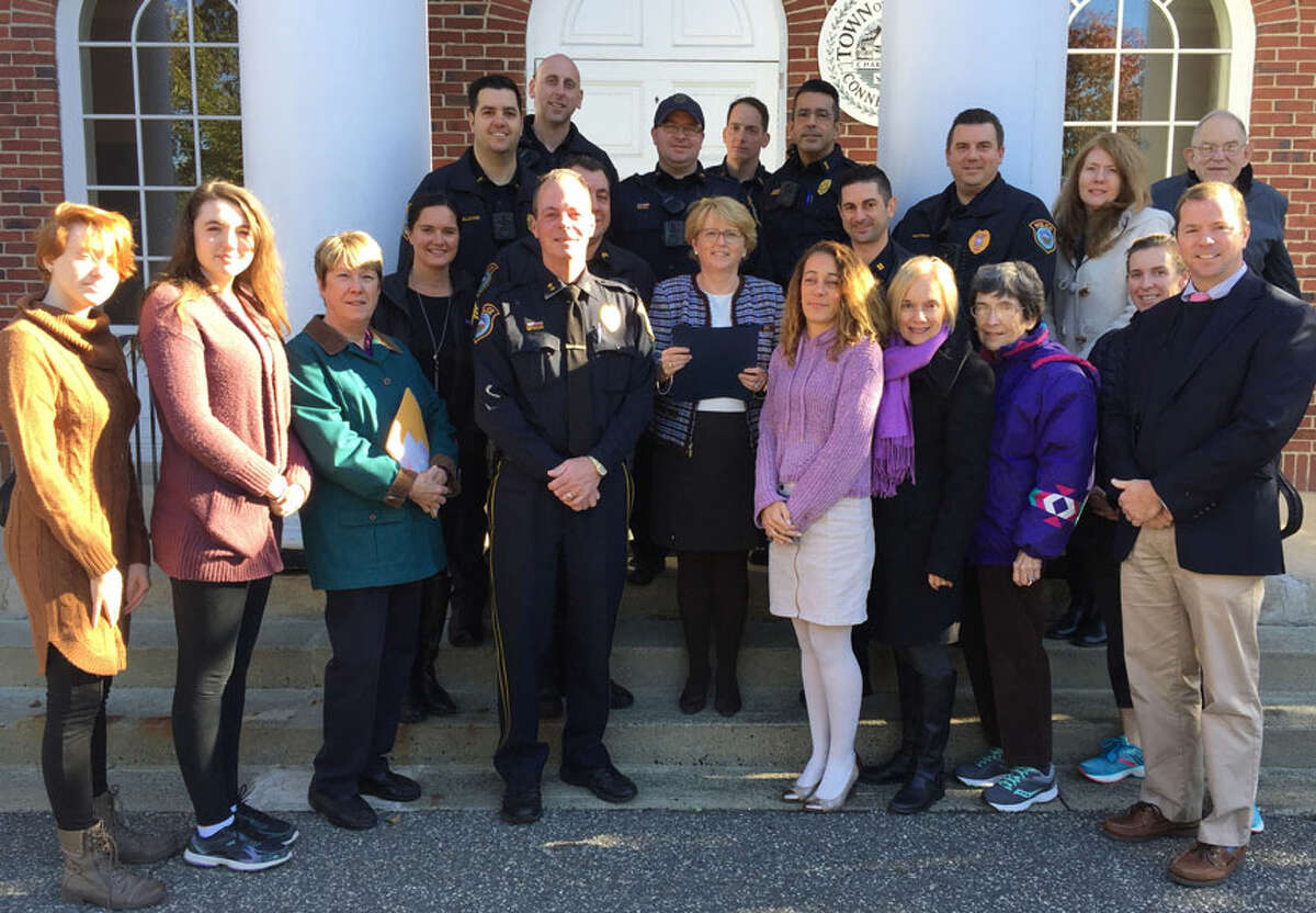 Those attending a reading of a domestic violence awareness proclamation, front row, from left, Macaire McNamara, Lauren McNamara, Kris Fager, Police Chief John Lynch, Kim Zemo, Margaret Creeth, Barbara Holdridge, and Dr. Kevin Smith. Second row, Sarah Heath, Sgt. Anthony Cocco, First Selectwoman Lynne Vanderslice, Captain Rob Cipolla, Maureen McGrath. Third row, Officer Rob Smaldone, Officer Jon Patry, Officer Vincent Penna, Lt. David Hartman, Jennifer McNamara, and Jerry Holdridge. Back row, Officer Frank Razzaia and Officer Joseph Caloross