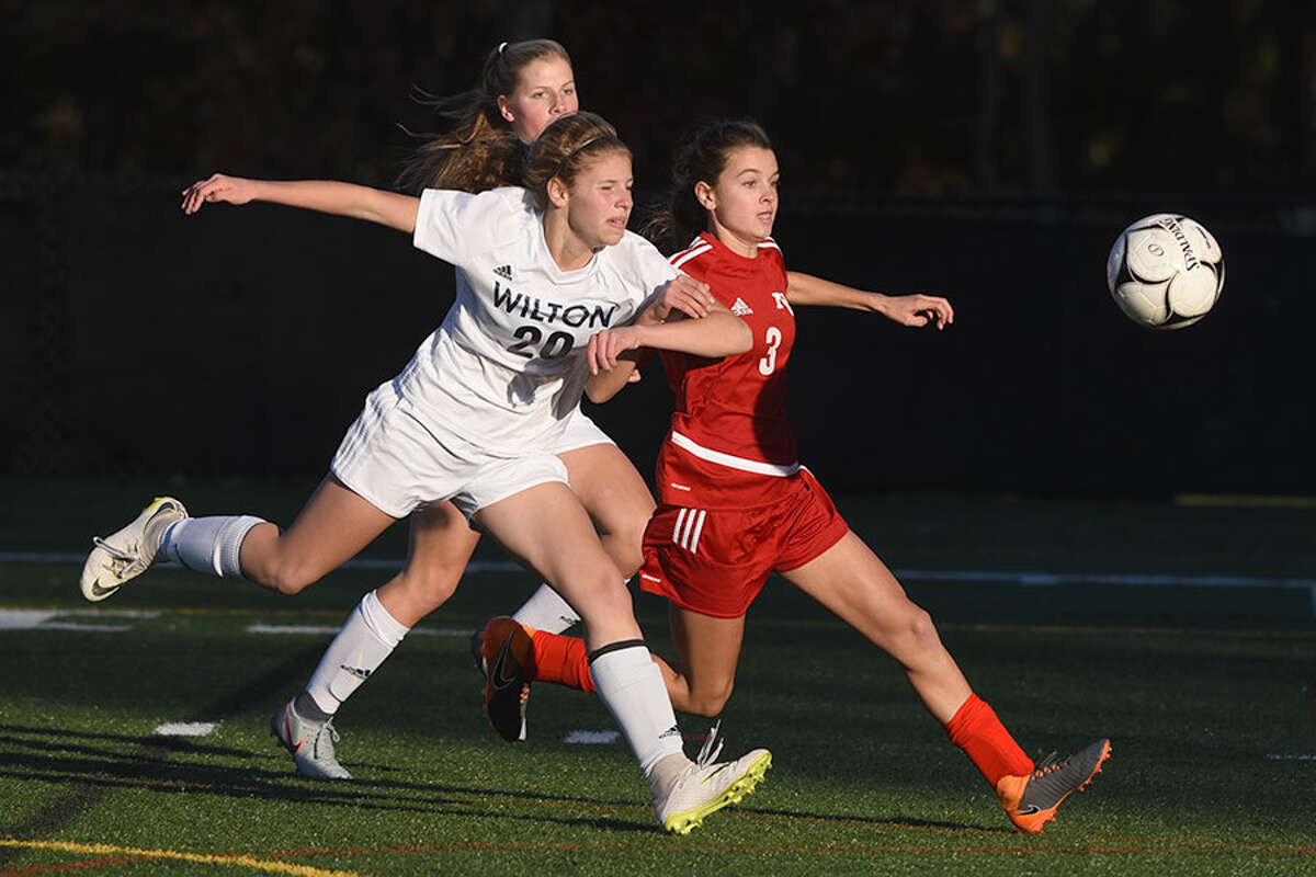 New Canaan’s Dillyn Patten and Wilton’s Maddie Wecker pursue the ball during the FCIAC girls soccer quarterfinals Thursday at Dunning Field. — Dave Stewart photo