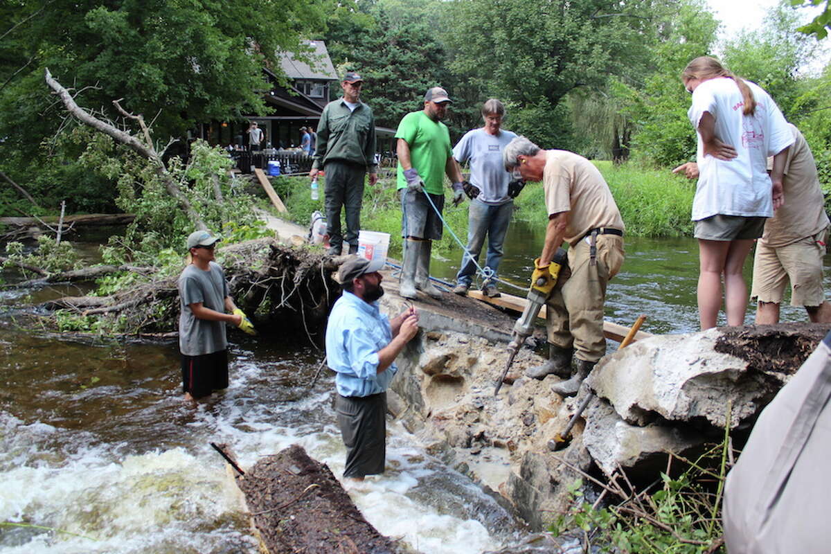 Gerrald Berrafati and Jeff Yates (in water) and Bill Carpenter of Ridgefield (on dam) of the Mianus Chapter of Trout Unlimited work with members of the Connecticut Department of Energy and Environmental Protection's Diadromous Fish Restoration Project to remove the Cannondale Dam on Aug. 19, 2018. In green holding a safety cord is Fisheries Biologist Dave Ellis, to his left is Seasonal Resource Assistant Kirk McPherson, and Fisheries Biologist Bruce Williams is operating the jackhammer. - John Kovach photo