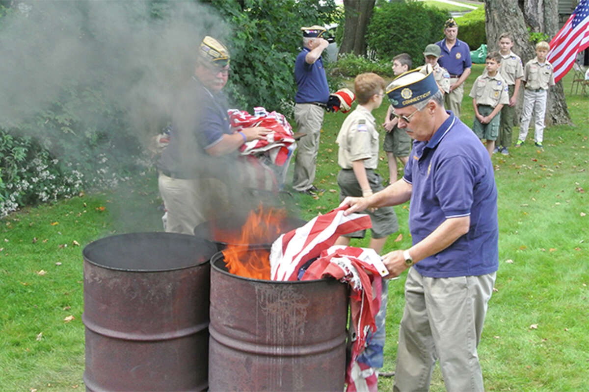 American Legion Post 86 Commander Don Hazzard places a flag in the flames as Adjutant Tom Moore receives another flag for retirement in 2017. — Jeannette Ross photo